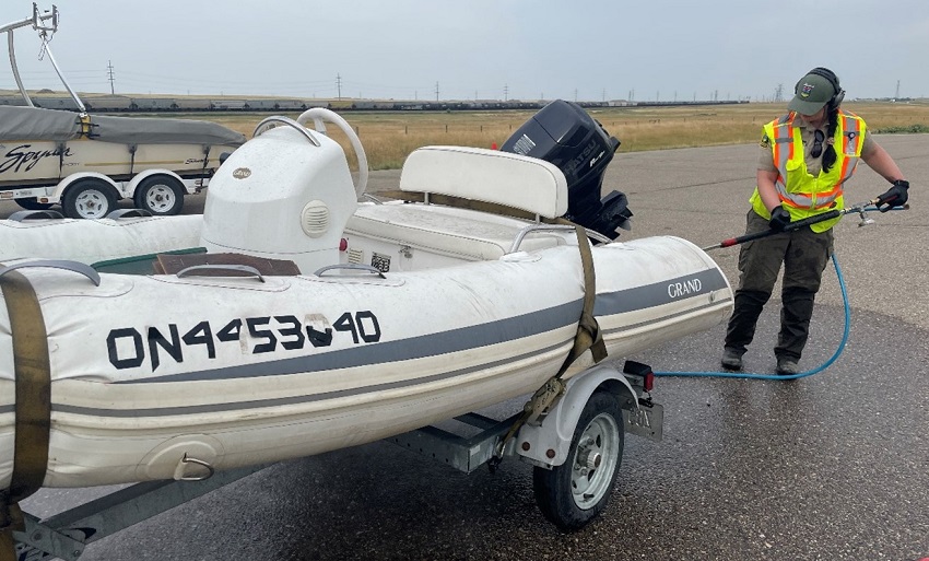 Invasive species officials decontaminate a watercraft at an inspection station