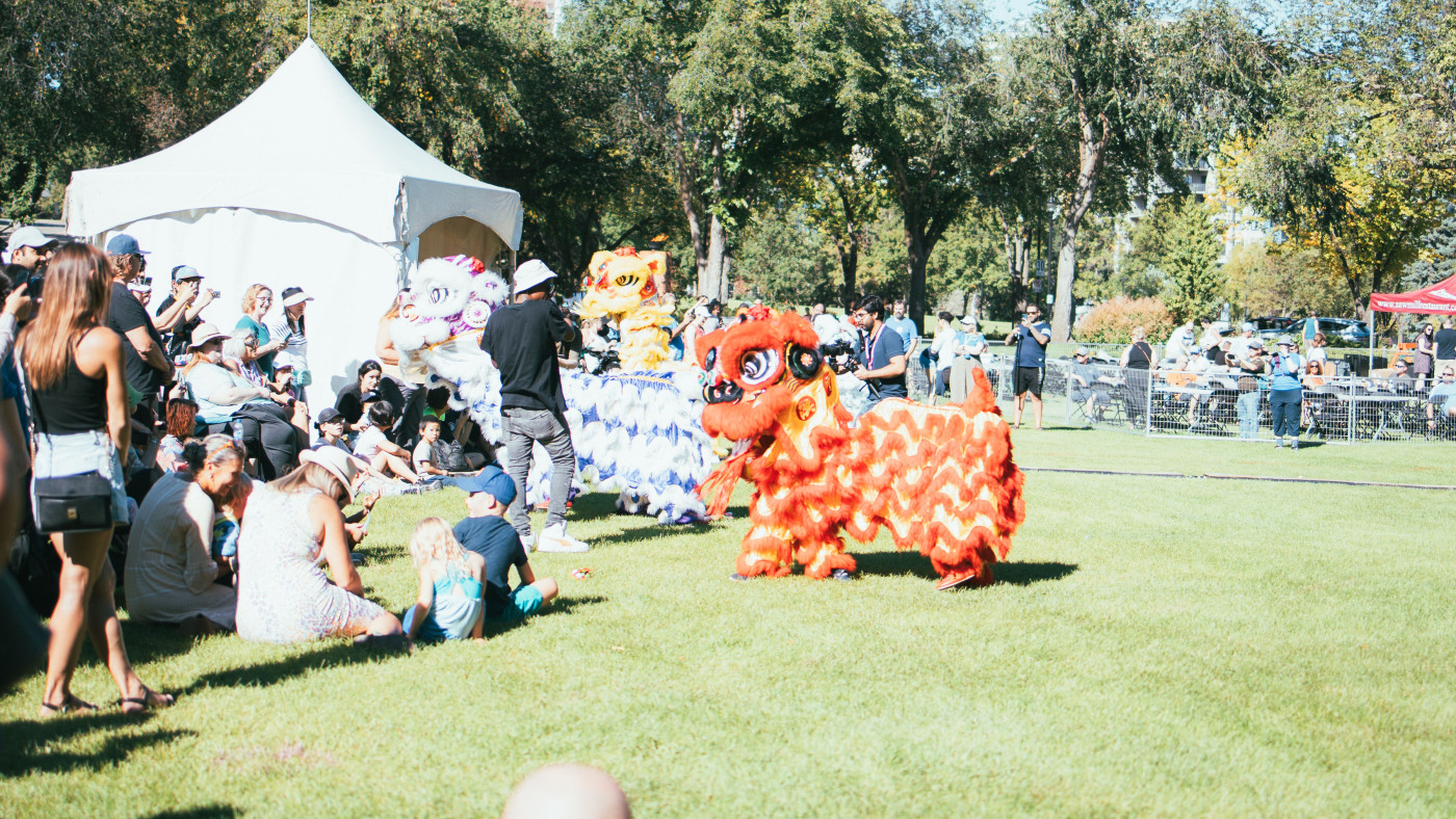 Dragon dancers gather around a tent as people look on.