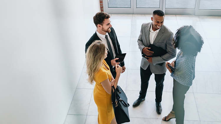 Co-workers stand together in a hallway talking.