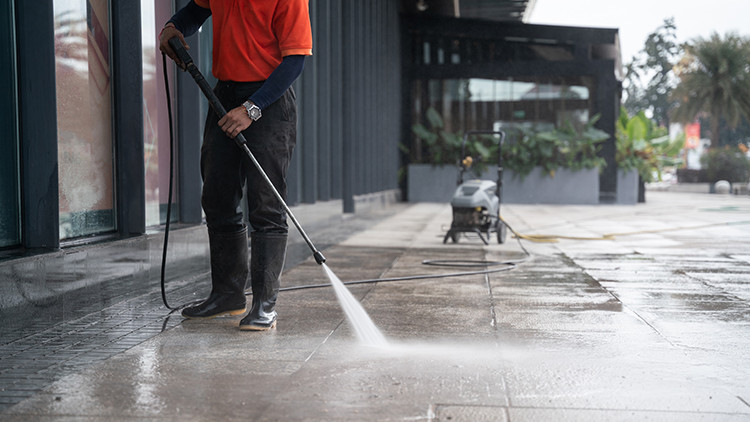 Photo of person power washing a stone pation