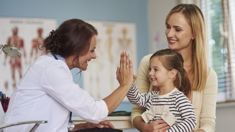 Mother and daughter in doctors office, girl and doctor high 5 each other