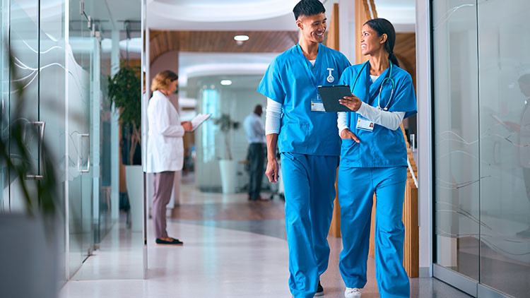 Two young medical personnel walking down a hallway